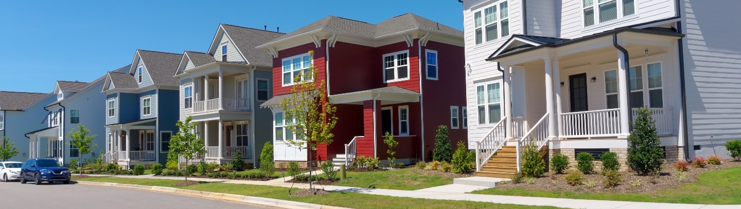 Six 20th-century Traditional-style homes line street in a suburban planned community that needs HOA insurance.