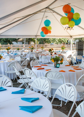 Tables under a tent with multi-color decorations for a private event.