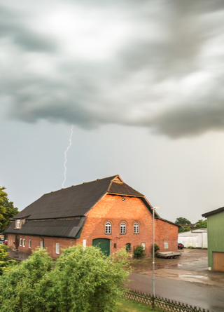 Storm clouds and lightning above a farm and outbuildings.  