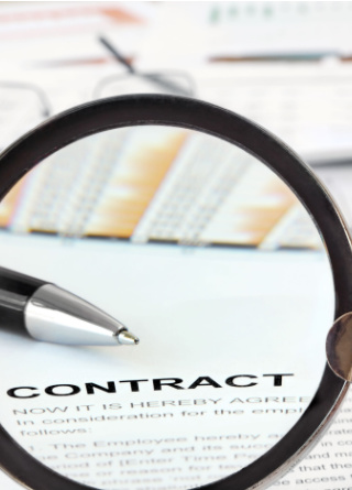 Magnifying glass over contract agreement with pen in view and more papers in the background.