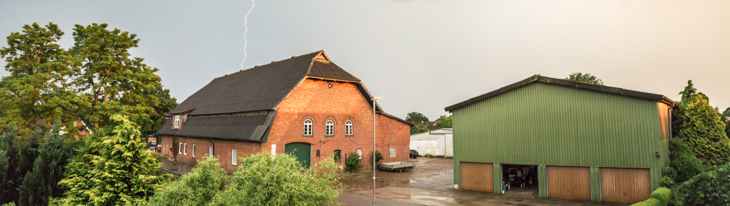 Storm clouds and lightning above a farm and outbuildings.  