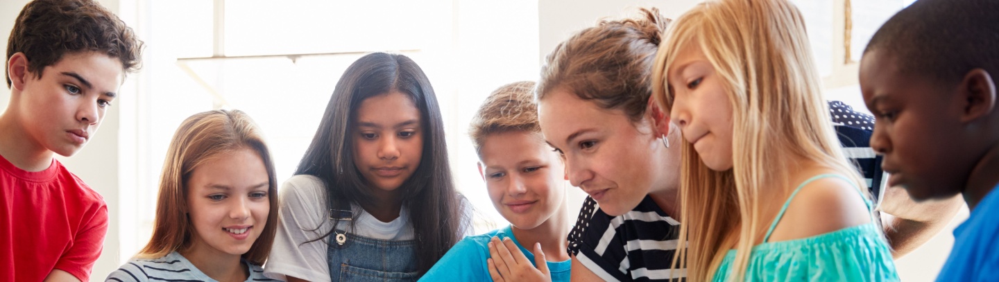 A group of preteens gather around their laptops during an after-school youth program.