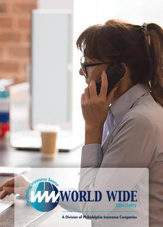 A female temporary office worker multitasking between a phone call and her computer. 