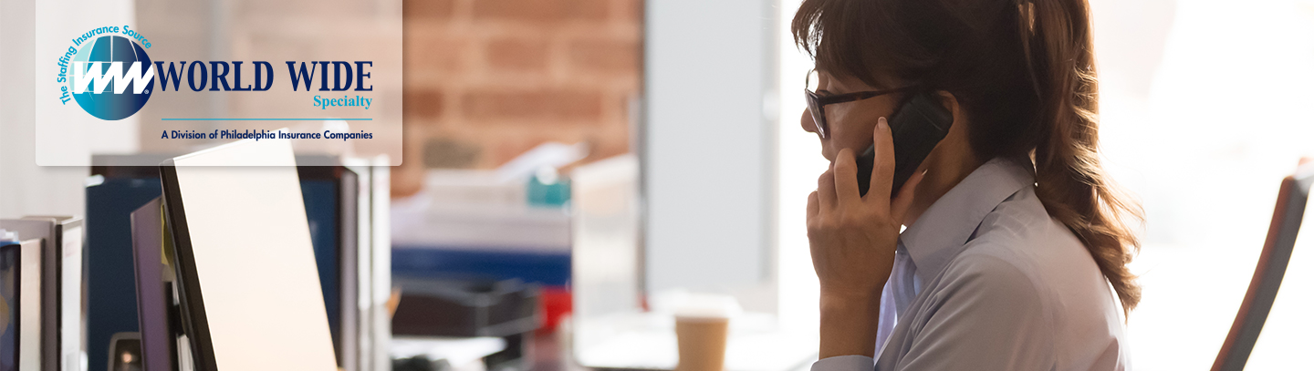 A female temporary office worker multitasking between a phone call and her computer. 