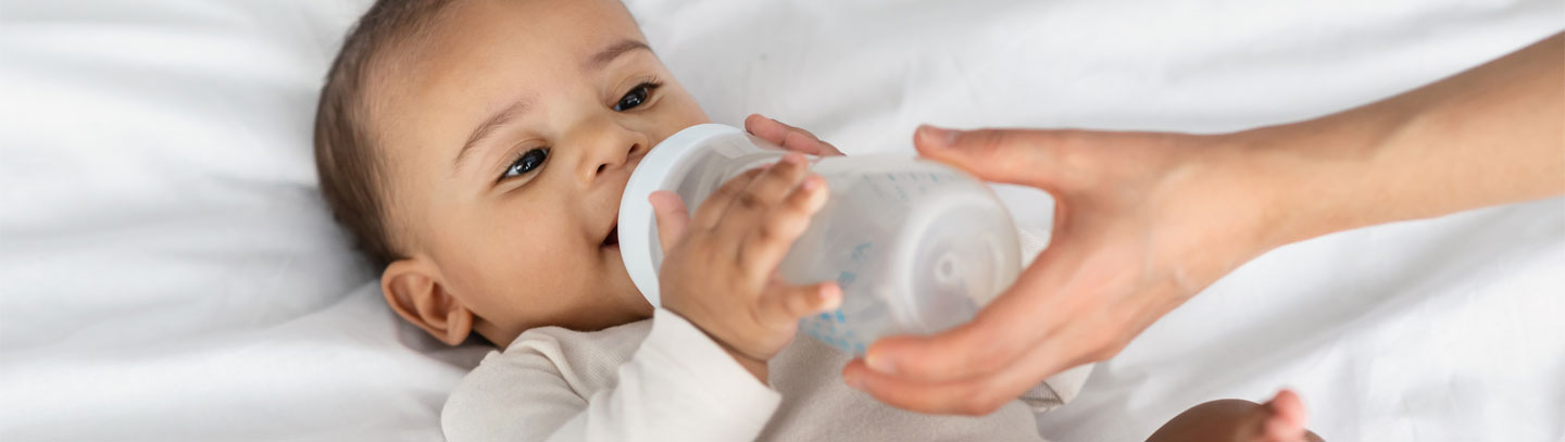 African American infant drinking from a baby bottle. 