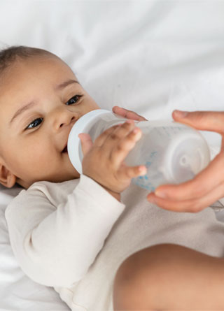 African American infant drinking from a baby bottle. 