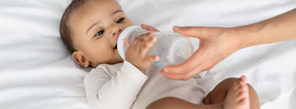 African American infant drinking from a baby bottle. 
