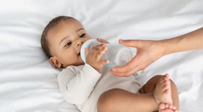 African American infant drinking from a baby bottle. 