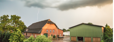 Storm clouds and lightning above a farm and outbuildings.  