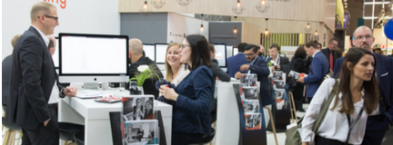 Crowd milling around trade show and conversing with businesses.