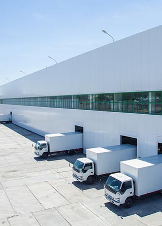 White box trucks lined up in garage doors of a warehouse.  