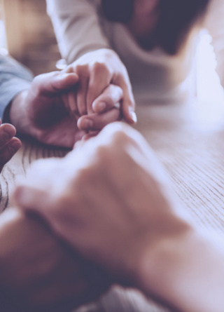 Circle of adults holding hands at a table. 