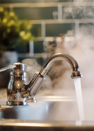 Hot water flowing from a modern faucet with steam rising, signifying hygiene, warmth, and the comforts of a well-equipped home Stock Photo | Adobe Stock 
