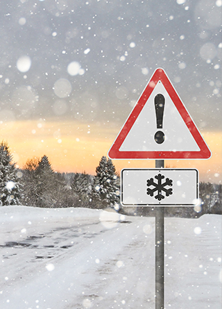 Snowy landscape with a traffic sign warning of winter weather