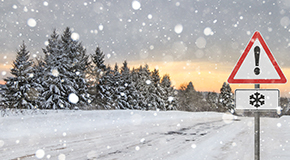 Snowy landscape with a traffic sign warning of winter weather