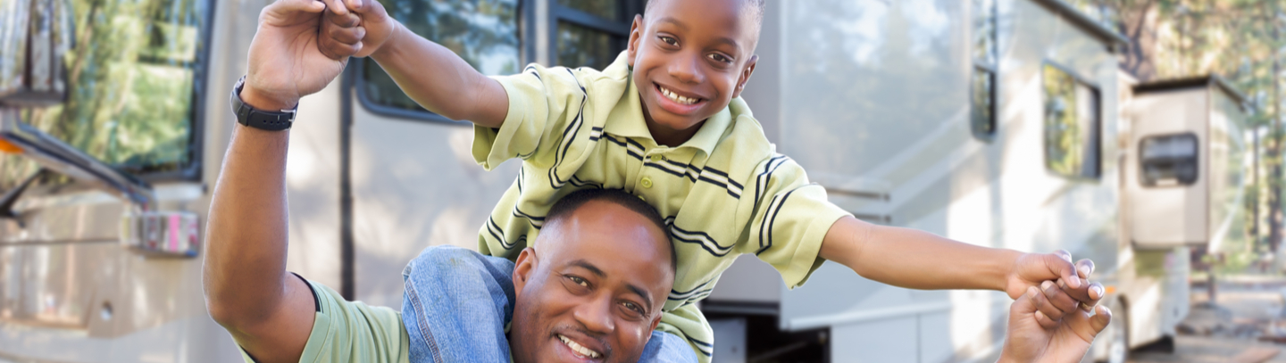 Happy father and son in front of their camper. 