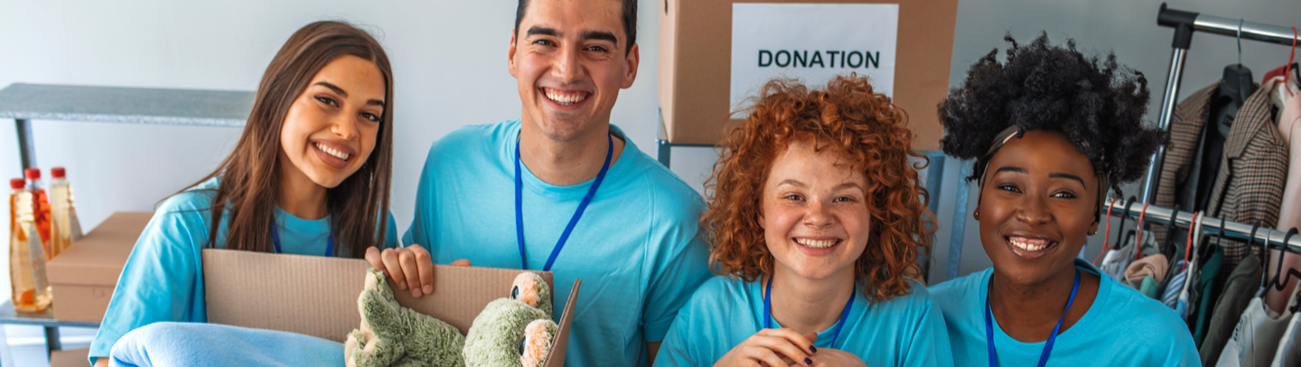 Group of four people smiling at camera collecting various donations. 