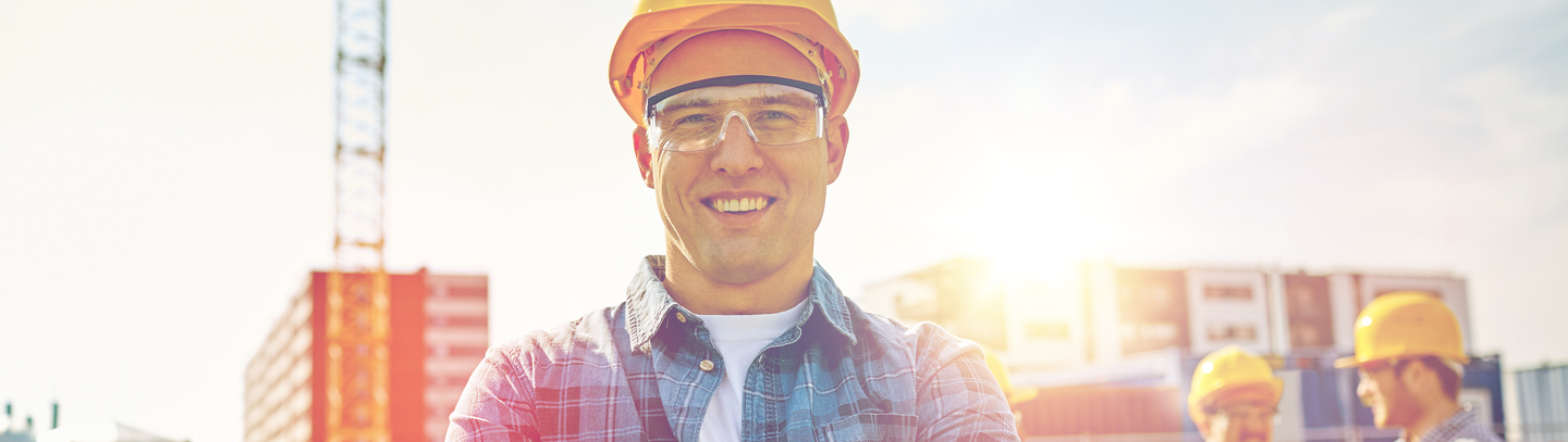 Small business construction manager wearing a hard hat with job site in the background.