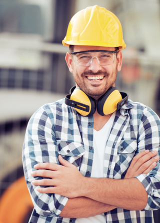 Smiling construction worker wearing hard hat in front of bulldozer. 