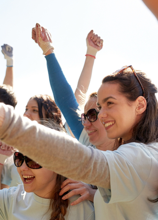 Group of happy young volunteers cheering as they work in the community