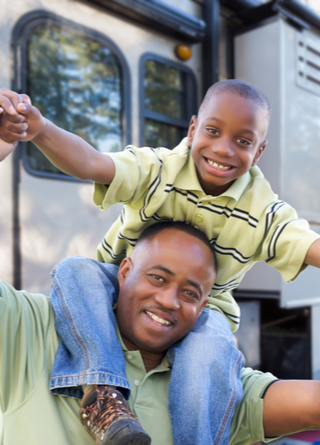 Happy father and son in front of their camper. 