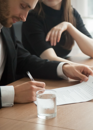 Businessman and woman look over the contract on the desk with a laptop.