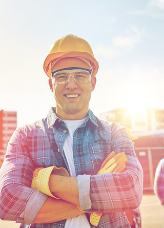 Small business construction manager wearing a hard hat with job site in the background.