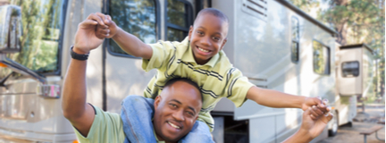 Happy father and son in front of their camper. 