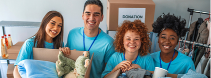 Group of four people smiling at camera collecting various donations. 