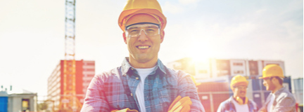 Small business construction manager wearing a hard hat with job site in the background. 